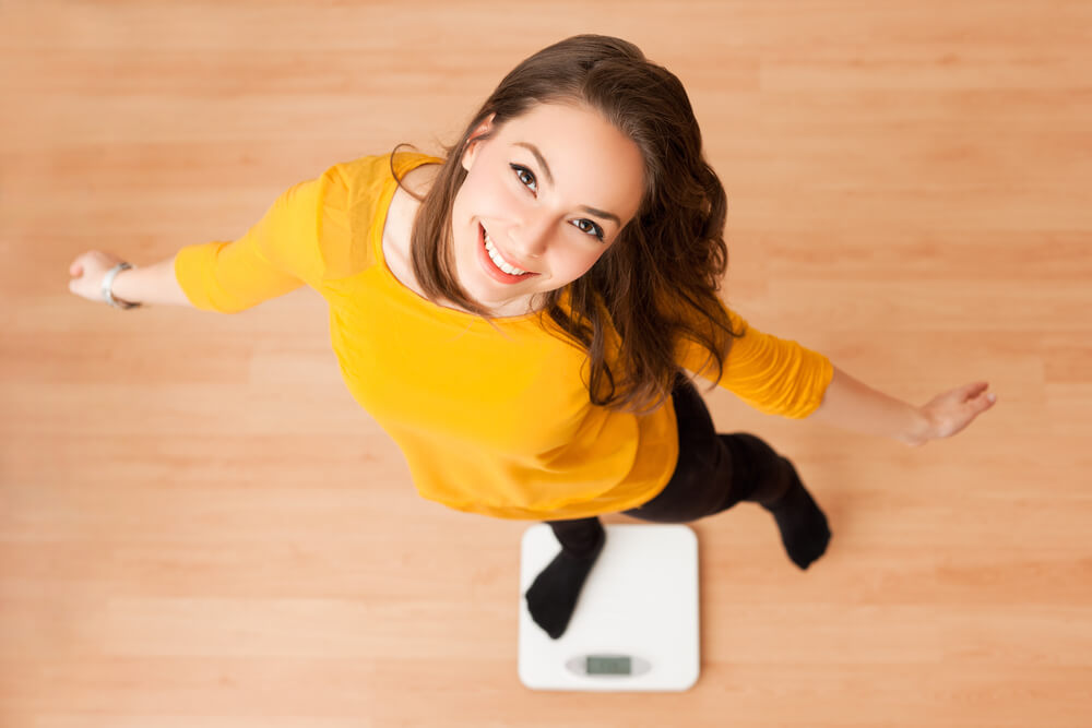 Portrait of Young Brunette Beauty Using Household Scale.