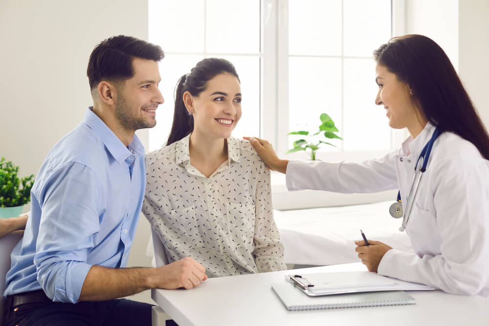 Female Doctor Consulting Young Couple Patients in Fertility Clinic About IVF