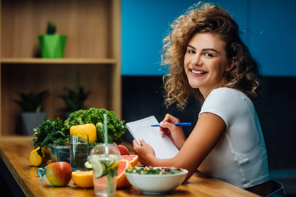 Nutritionist Working In Office Doctor Writing Diet Plan On Table And Using Vegetables Sport Trainer Lifestyle