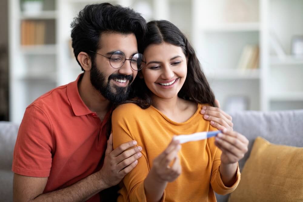 Portrait Of Happy Young Indian Couple Looking At Positive Pregnancy Test