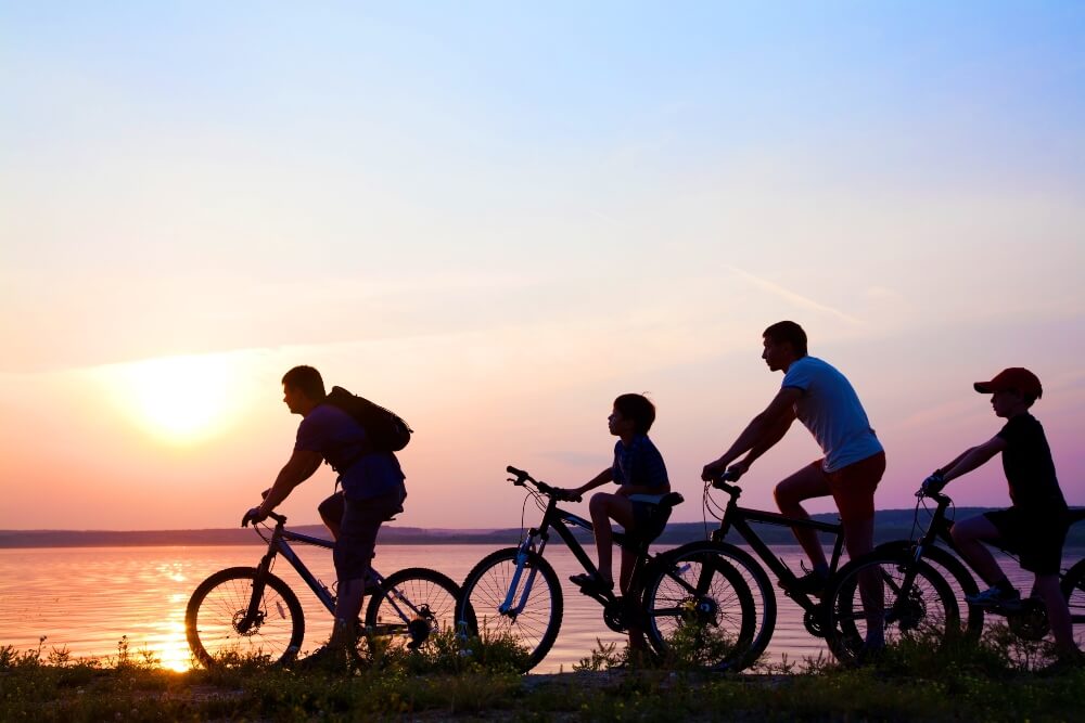 Family on Bicycles Admiring the Sunset on the Lake 