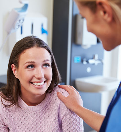 Female-Patient-Being-Reassured-By-Doctor-In-Hospital-Room