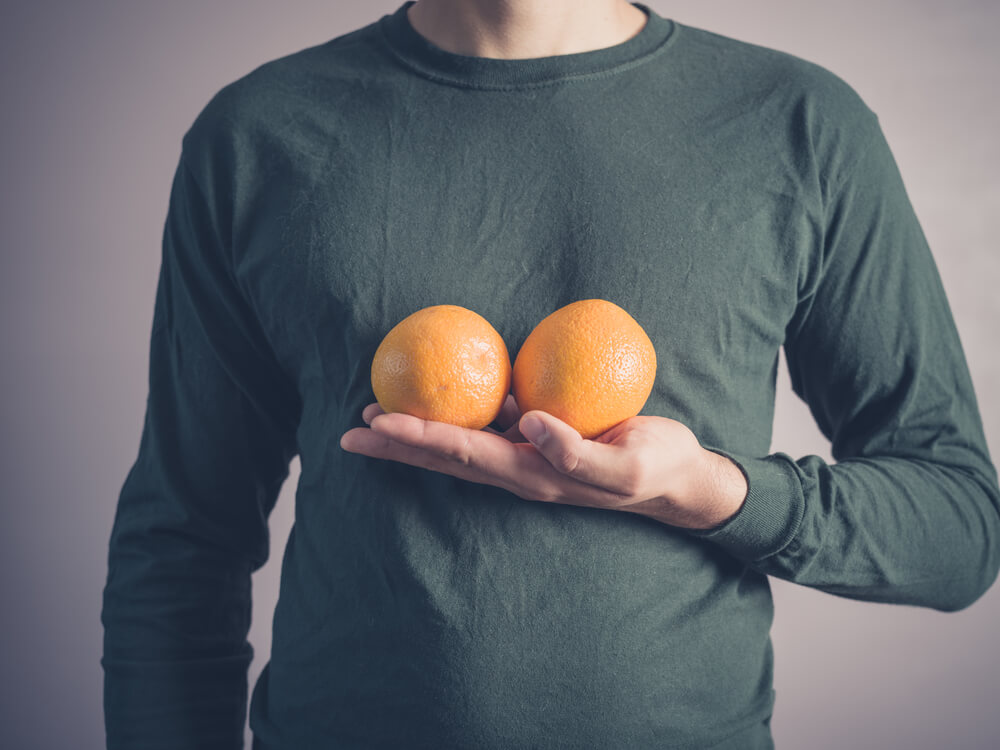 Young Man Holding Oranges Next to His Chest