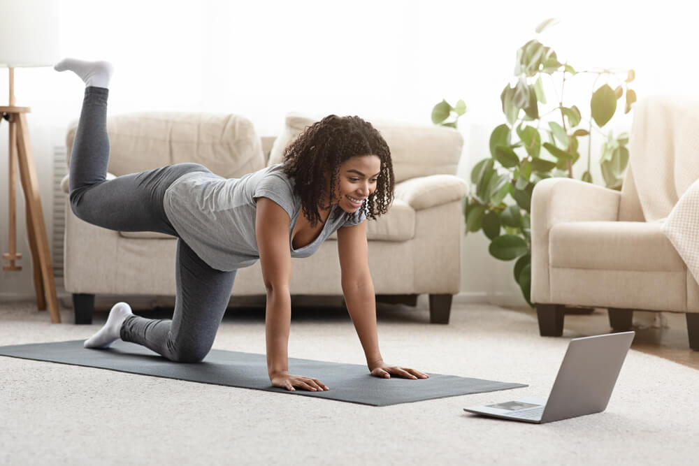 Fit Young Woman Excercising at Home, Watching Video Tutorial on Laptop