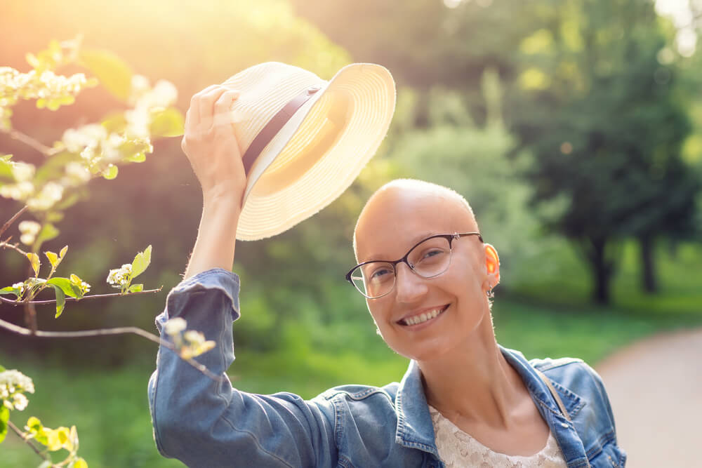 Happy Young Caucasian Bald Confident Hipster Woman Take off Hat and Enjoying Life After Surviving Breast Cancer.