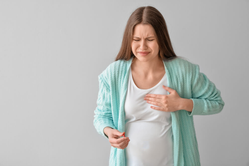 Ill Pregnant Young Woman With Pill on Grey Background