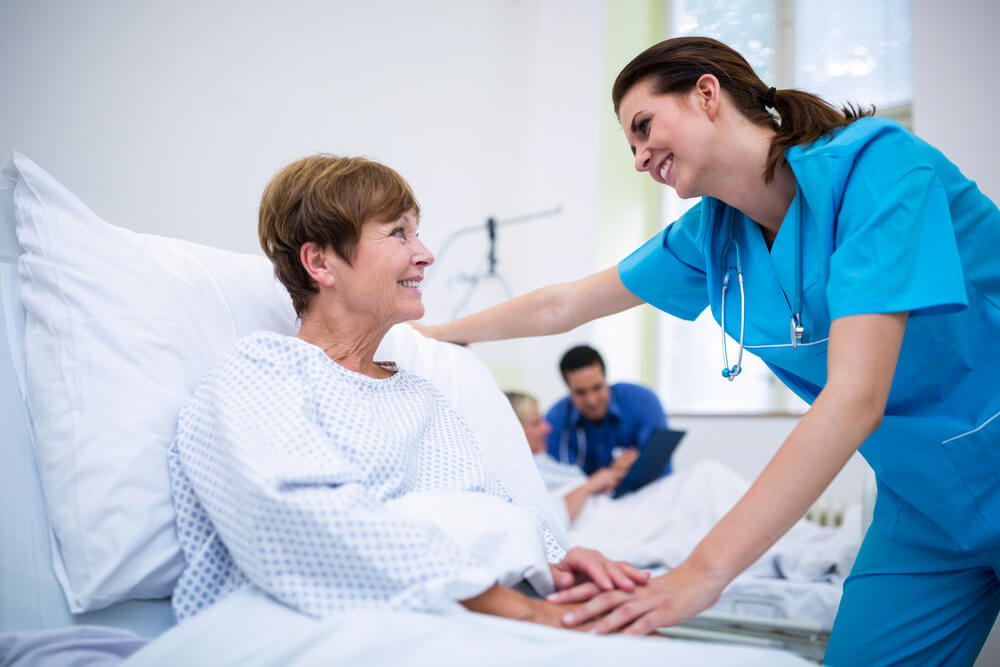 Nurse Consoling a Patient Laying in Bed in a Hospital