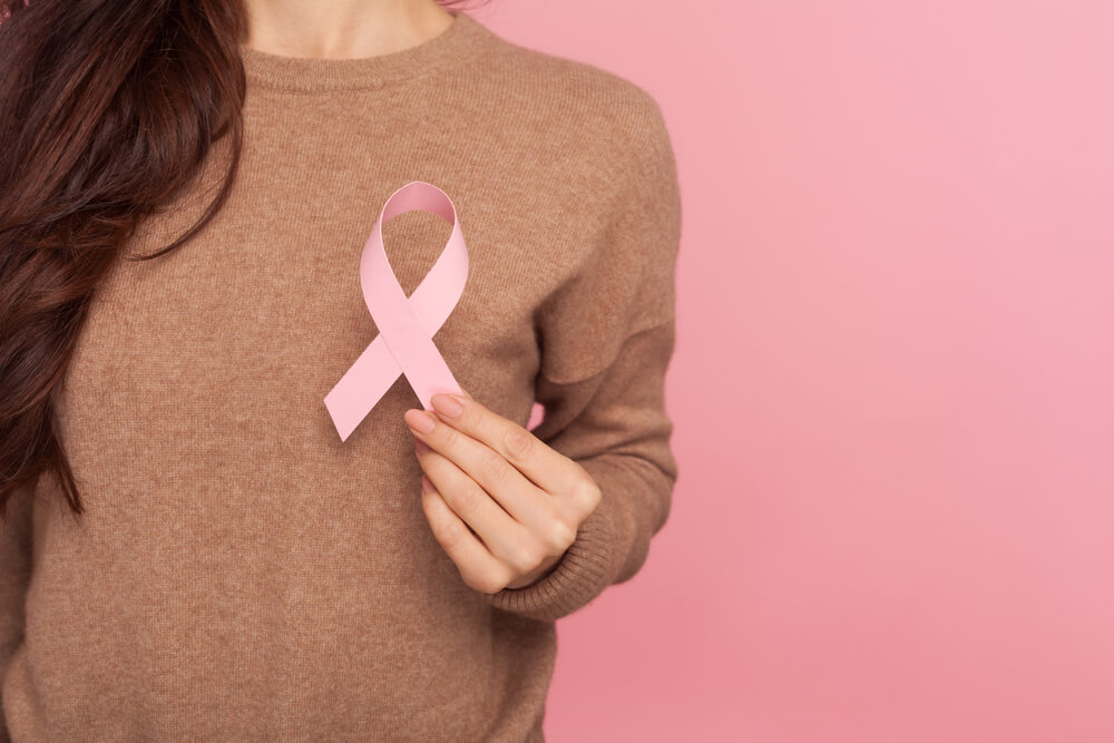 Female Health Check Awareness. Closeup of Young Woman in Pullover Holding Pink Ribbon