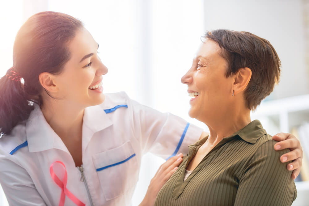 Pink Ribbon for Breast Cancer Awareness. Female Patient Listening to Doctor in Medical Office. 