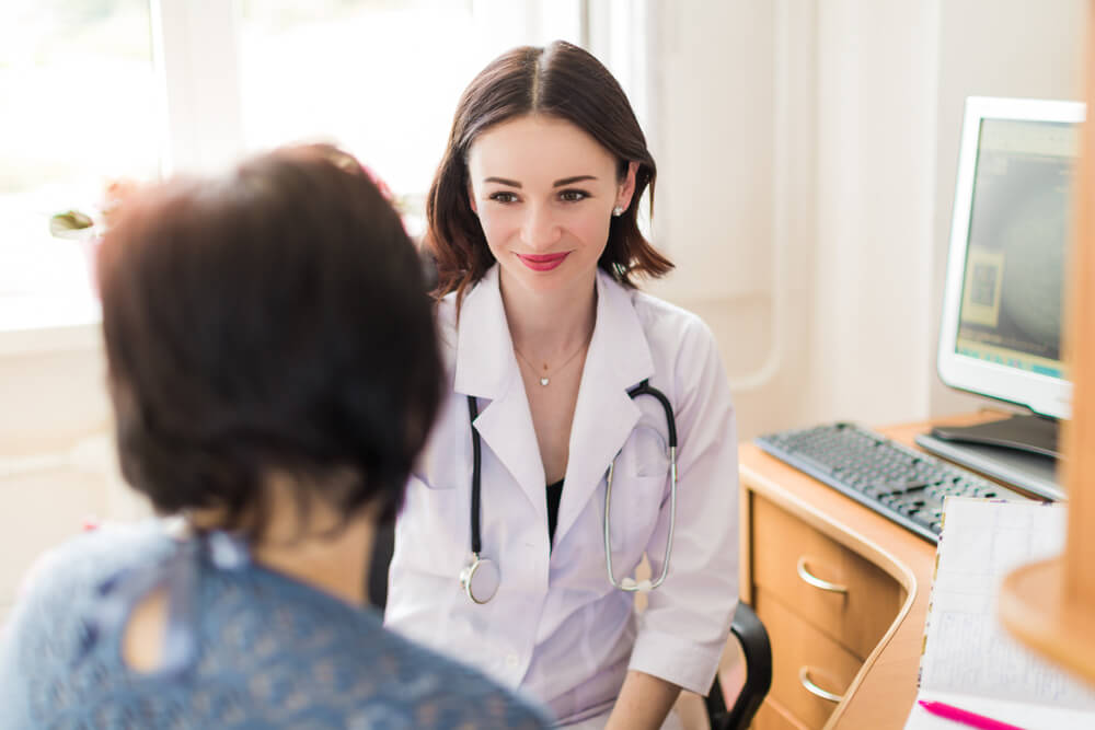 The Young Smiling Breast Specialist Talking With the Patient in Her Office