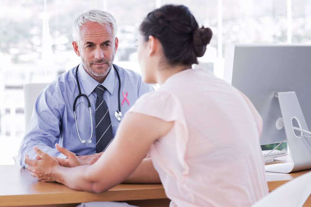 Pink Awareness Ribbon Against Patient Explaining Her Painful to Doctor