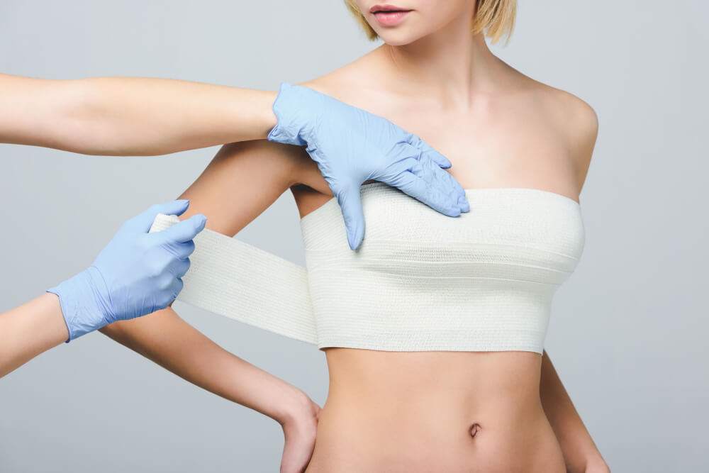 Cropped View of Plastic Surgeon Wrapping Female Breast With Bandage