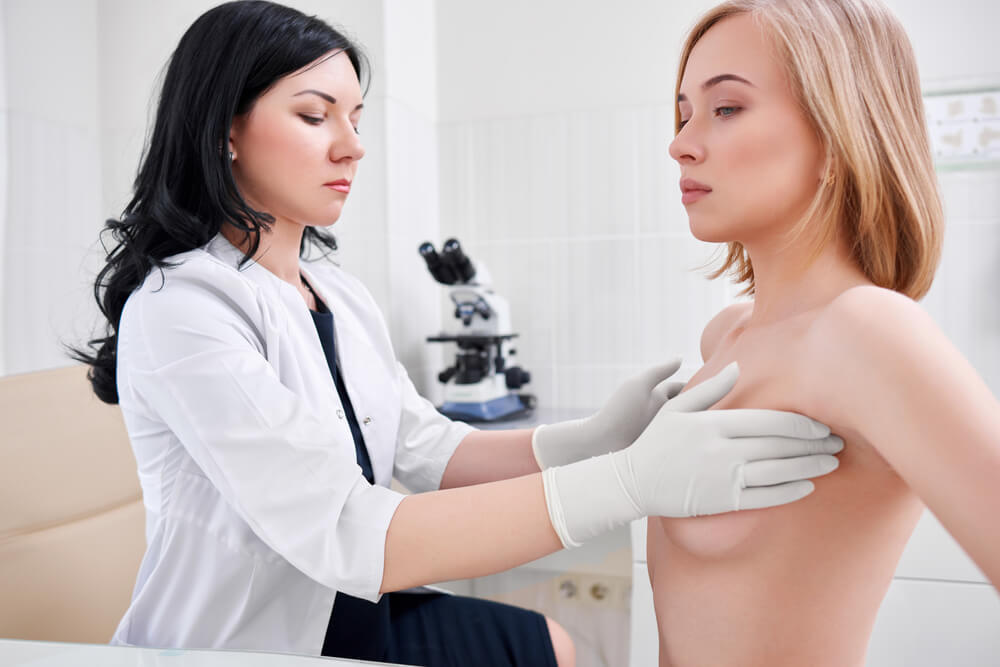 Young Woman Getting Her Breast Examined by Female Doctor Gynecologist 