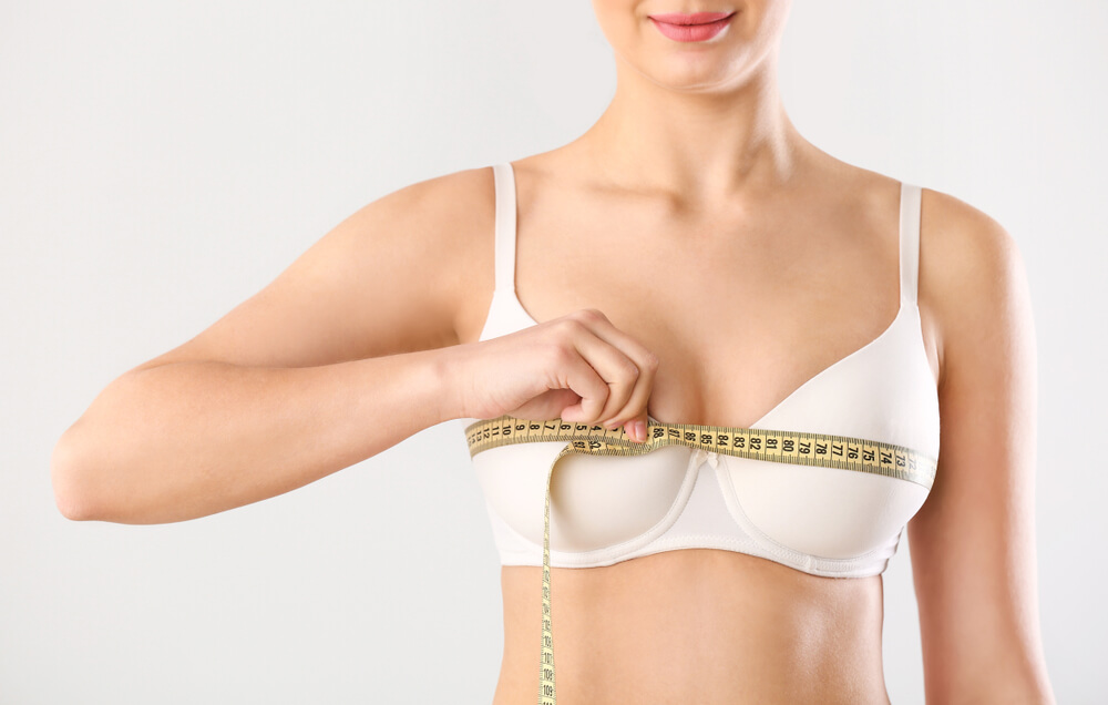 Young Woman Measuring Her Breast on White Background