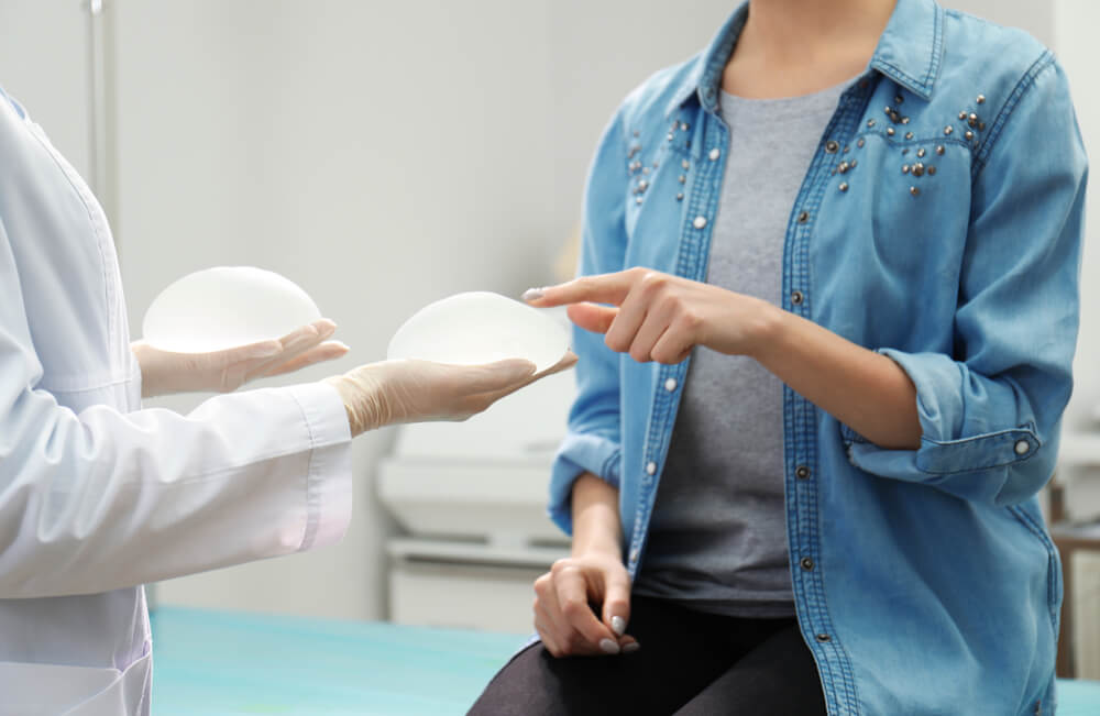 Doctor Showing Silicone Implants for Breast Augmentation to Patient in Clinic