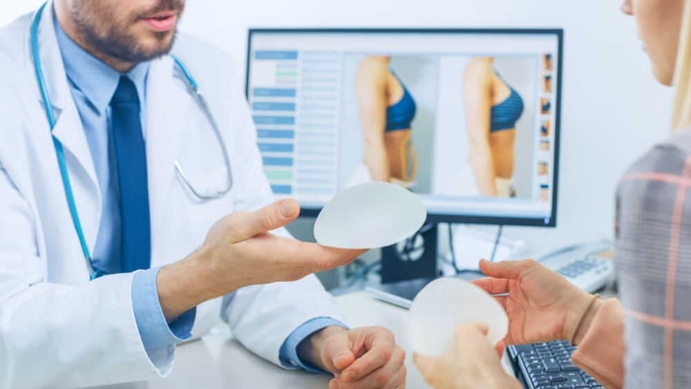 Doctor Showing Silicone Implants for Breast Augmentation to Patient in Clinic