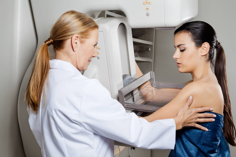 Female Doctor Assisting Young Patient Undergoing Mammogram