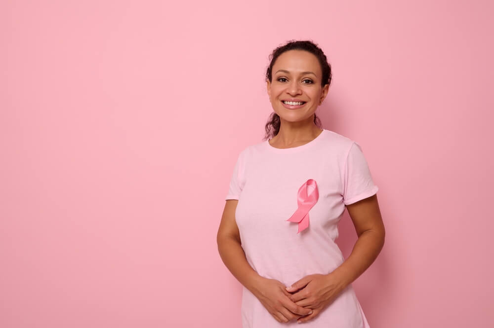 A Smiling Woman in Pink T-shirt With Pink Satin Ribbon Symbolizing International Breast Cancer Day