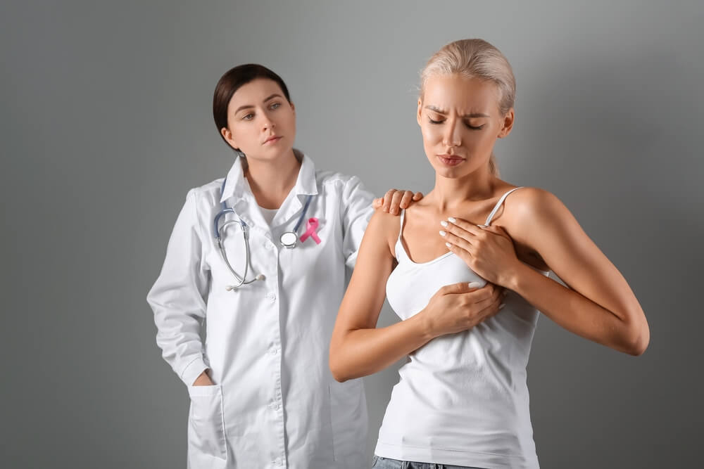 Doctor and Young Woman Checking Her Breast on Grey Background.