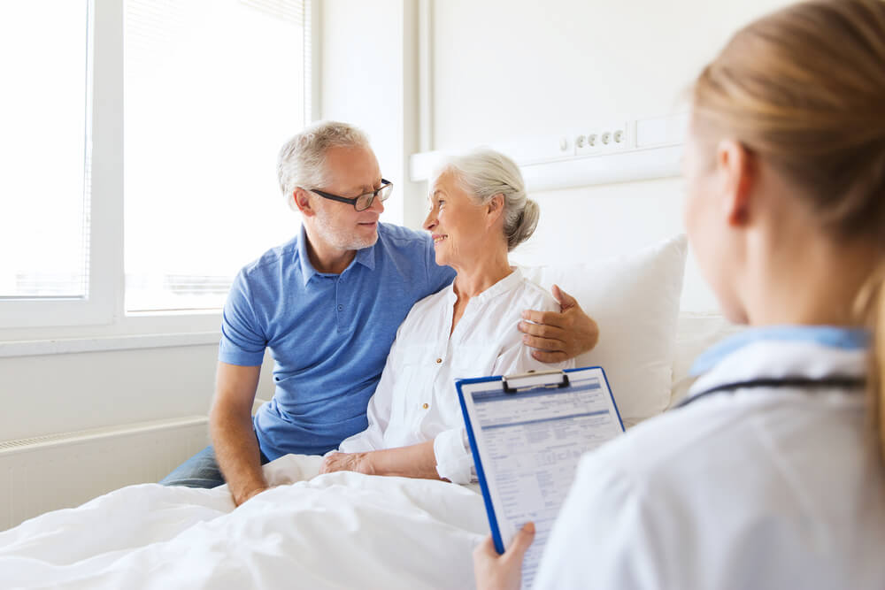 Medicine, Age, Health Care and People Concept - Senior Woman, Man and Doctor With Clipboard at Hospital Ward