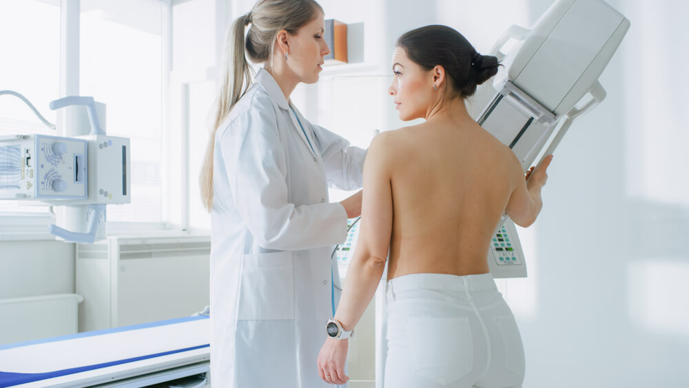 In the Hospital Mammography Technologist Doctor adjusts Mammogram Machine for Patient