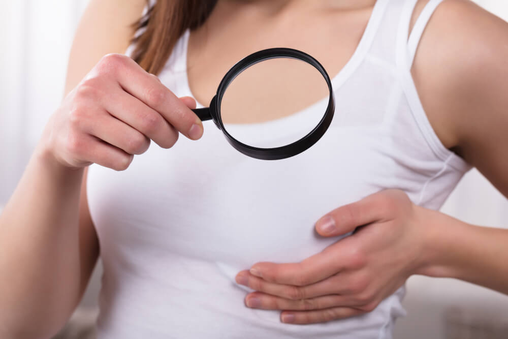 Woman Holding Magnifying Glass Showing Breast Care Concept