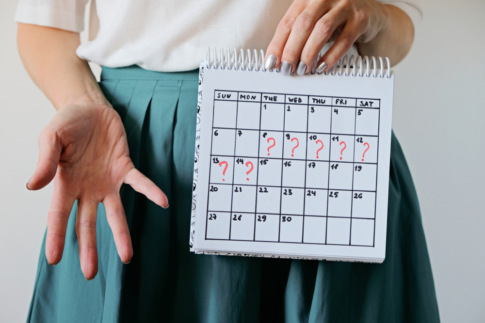A woman holding a calendar with marks representing missed days during regular period cycle.