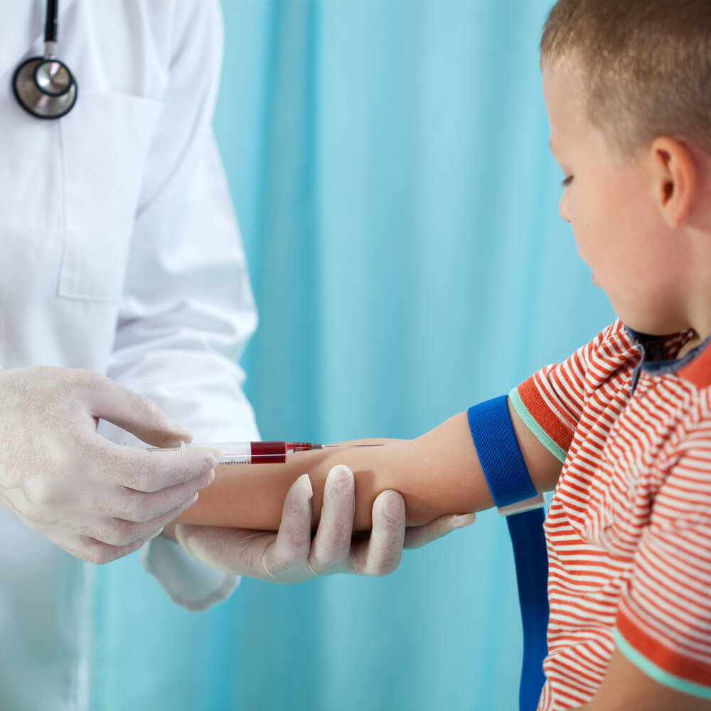 Pediatrician taking blood sample from a young boy