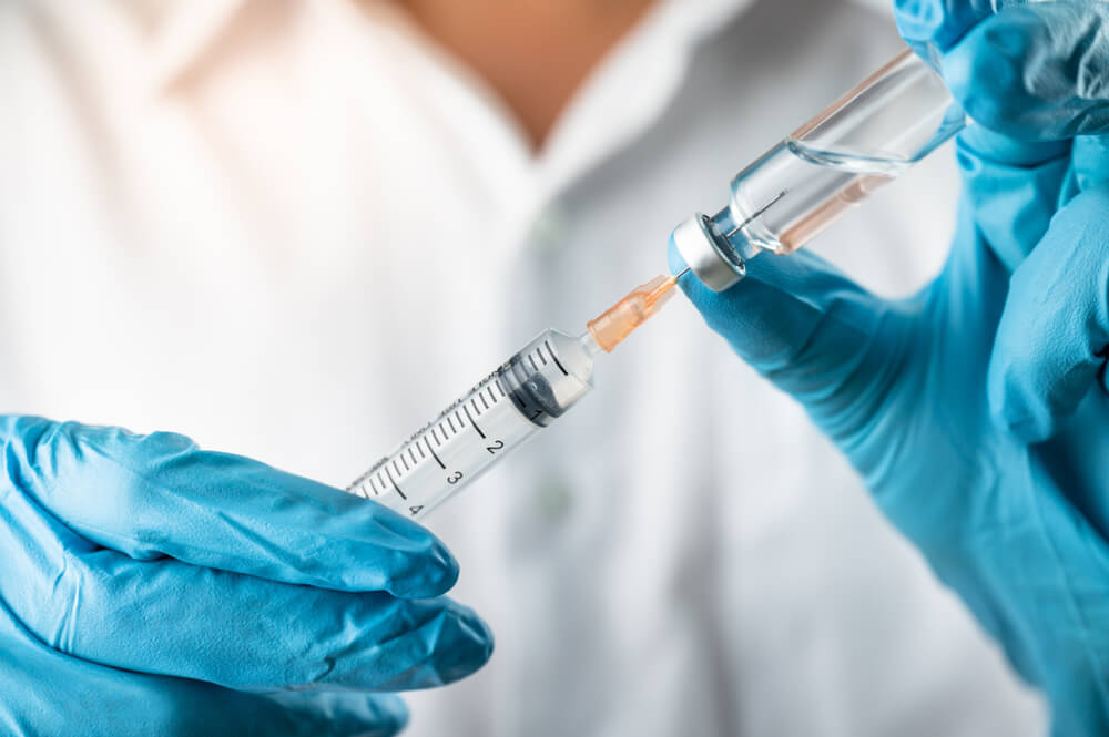 Doctor, nurse, scientist, researcher hand in blue gloves holding measles vaccine.
