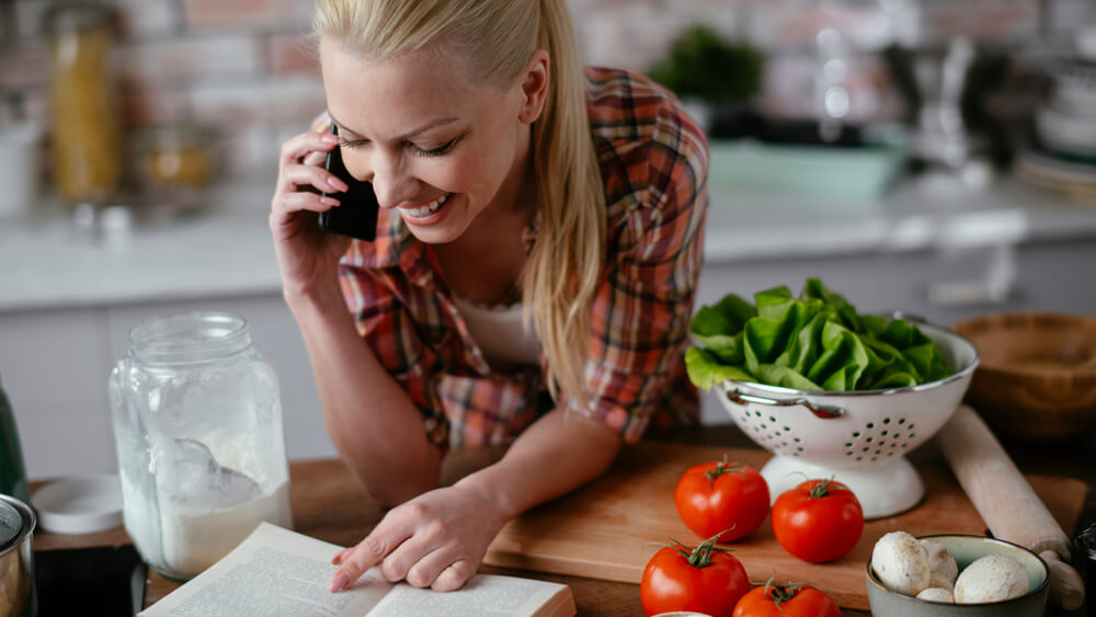 Young Woman Cooking in Kitchen and Talking on Phone