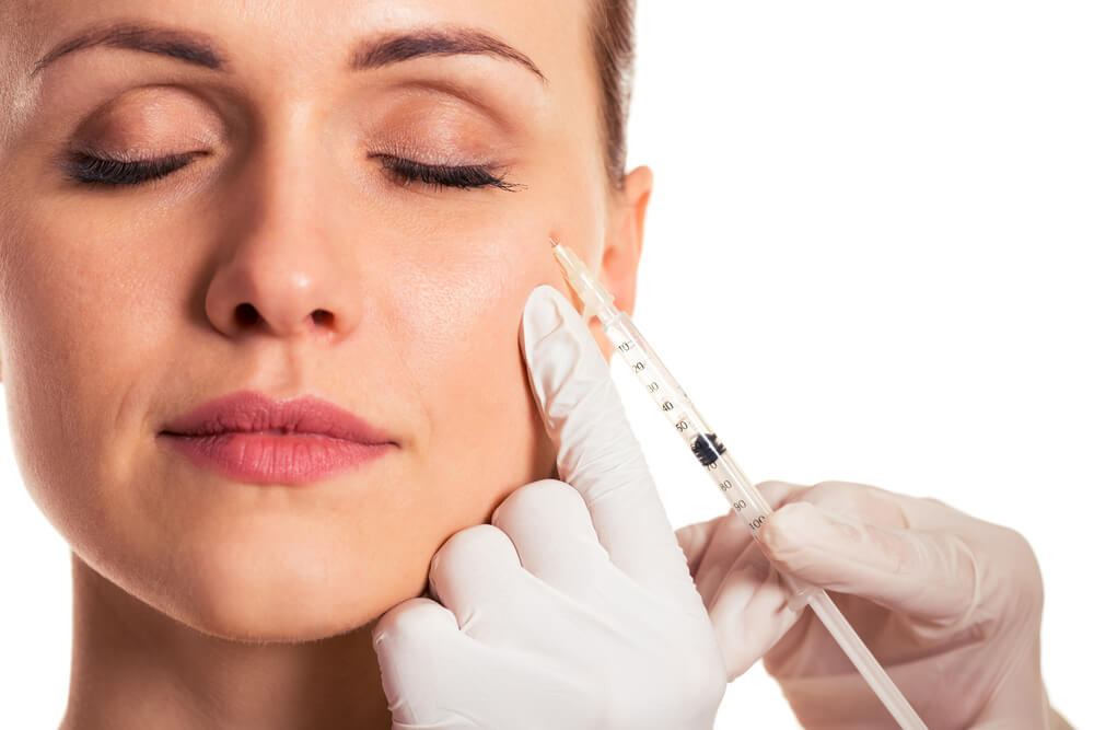 Beautiful Woman With Closed Eyes, Surgeon in Medical Gloves Is Making an Injection in Face