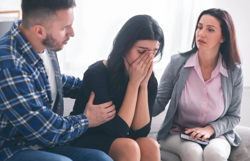 Man and Psychologist Comforting Crying Upset Woman at Psychological Consultation in Office