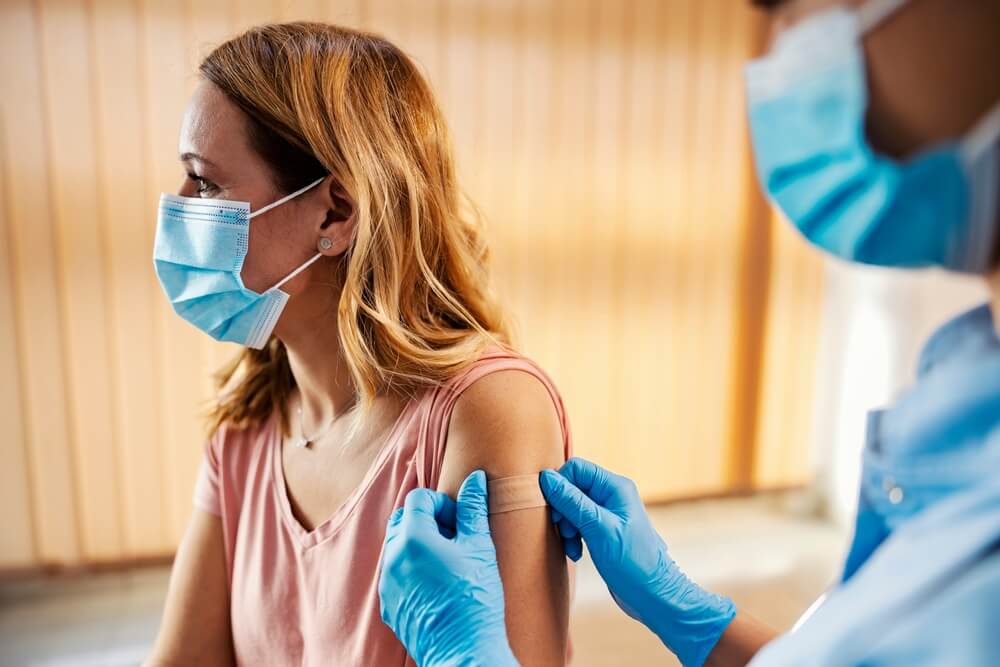 A Nurse in Hospital Putting Adhesive Plaster on Woman’s Arm After COVID 19 Vaccine.