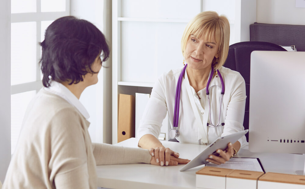 Doctor With Laptop and Pregnant Woman in Doctor’s Office