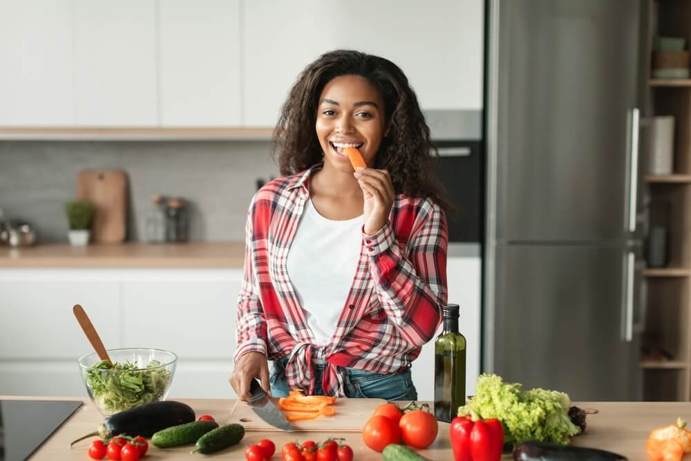 Dy Preparing Salad, Eating Carrot at Table With Organic Vegetables in Kitchen Interior