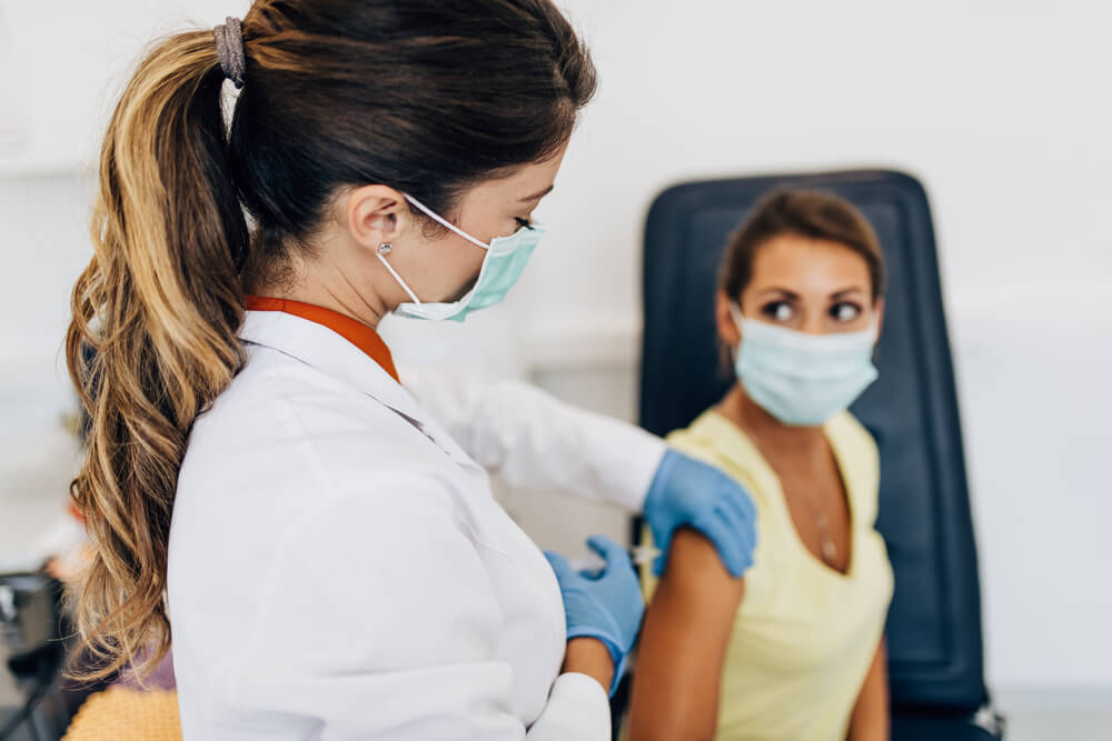 Female Doctor Or Nurse Giving Shot Or Vaccine To A Patients Shoulder Vaccination And Prevention Against Flu Or Virus Pandemic