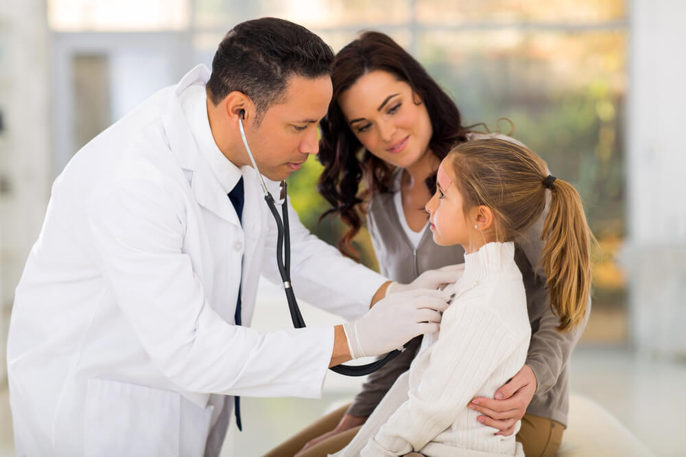 Caring Medical Doctor Examining a Little Girl in Office