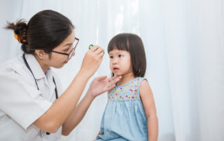 Asian Doctor Woman Examine Eyes of Little Asian Girl in the Clinic