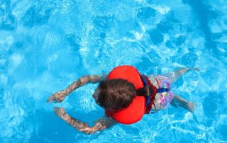 A Child Swimming in the Swimming Pool Wearing Life Jacket