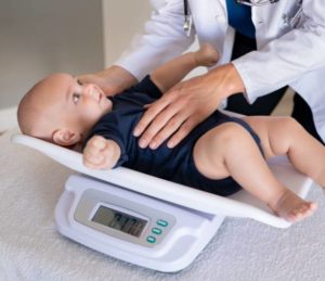 Baby at a pediatrician's office being weighed on a scale