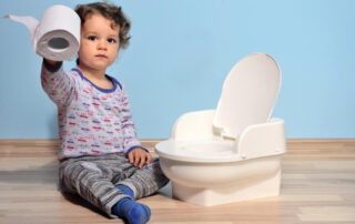 Baby Toddler Sitting on the Floor Near a Potty and Playing With Toilet Paper
