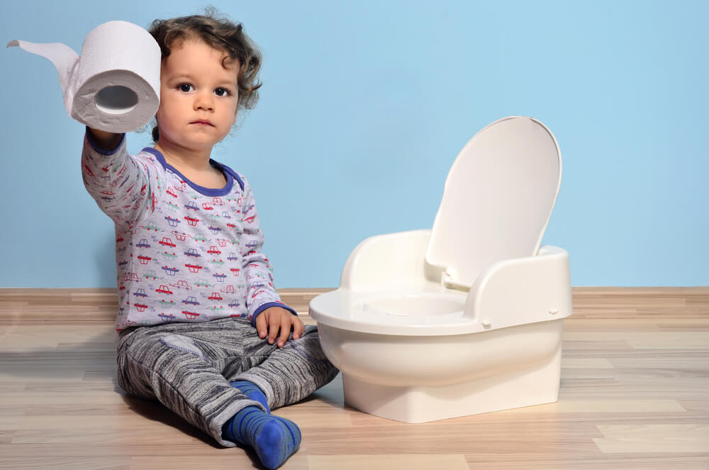 Baby Toddler Sitting on the Floor Near a Potty and Playing With Toilet Paper