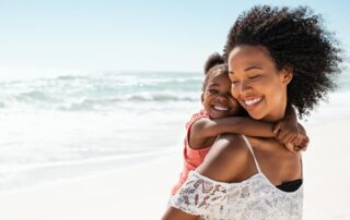 Smiling Young Black Mother and Beautiful Daughter Having Fun on the Beach