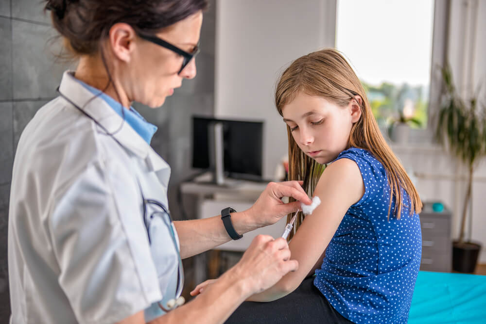 Pediatrics Female Doctor Giving a Young Girl a Vaccine Shot in the Arm