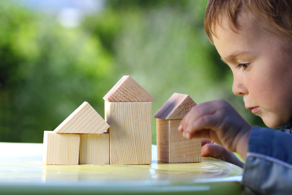 Boy Raises His Hand to the House From Wooden Cubes