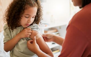 COVID Nurse Vaccinating Child Putting a Bandage on at a Clinic. Doctor Applying Plaster on Girl After an Injection at Health Centre