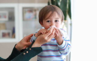 Adorable Baby Boy Blowing Nose Into Tissue Paper by His Mother at Home