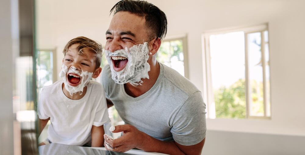 Father And Son Having Fun In A Bathroom Laughing Happily With Shaving Foam On Their Faces