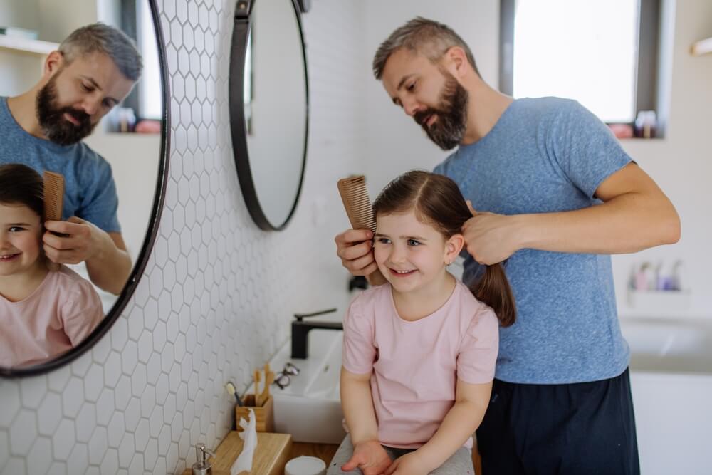 Father Brushing His Little Daughters Hair In Bathroom Morning Routine Concept