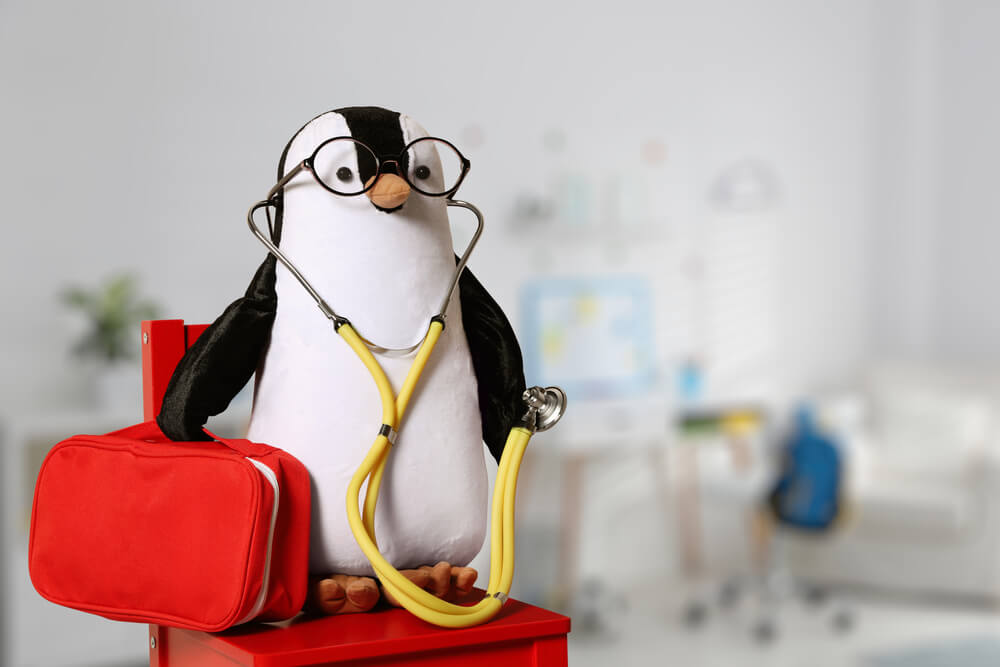 Toy Penguin With Eyeglasses Stethoscope and First Aid Bag Indoors